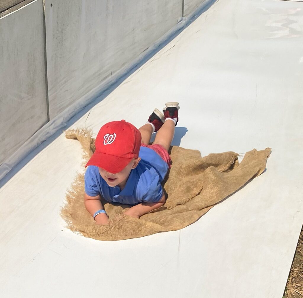 Child riding on a burlap sack across a slide.